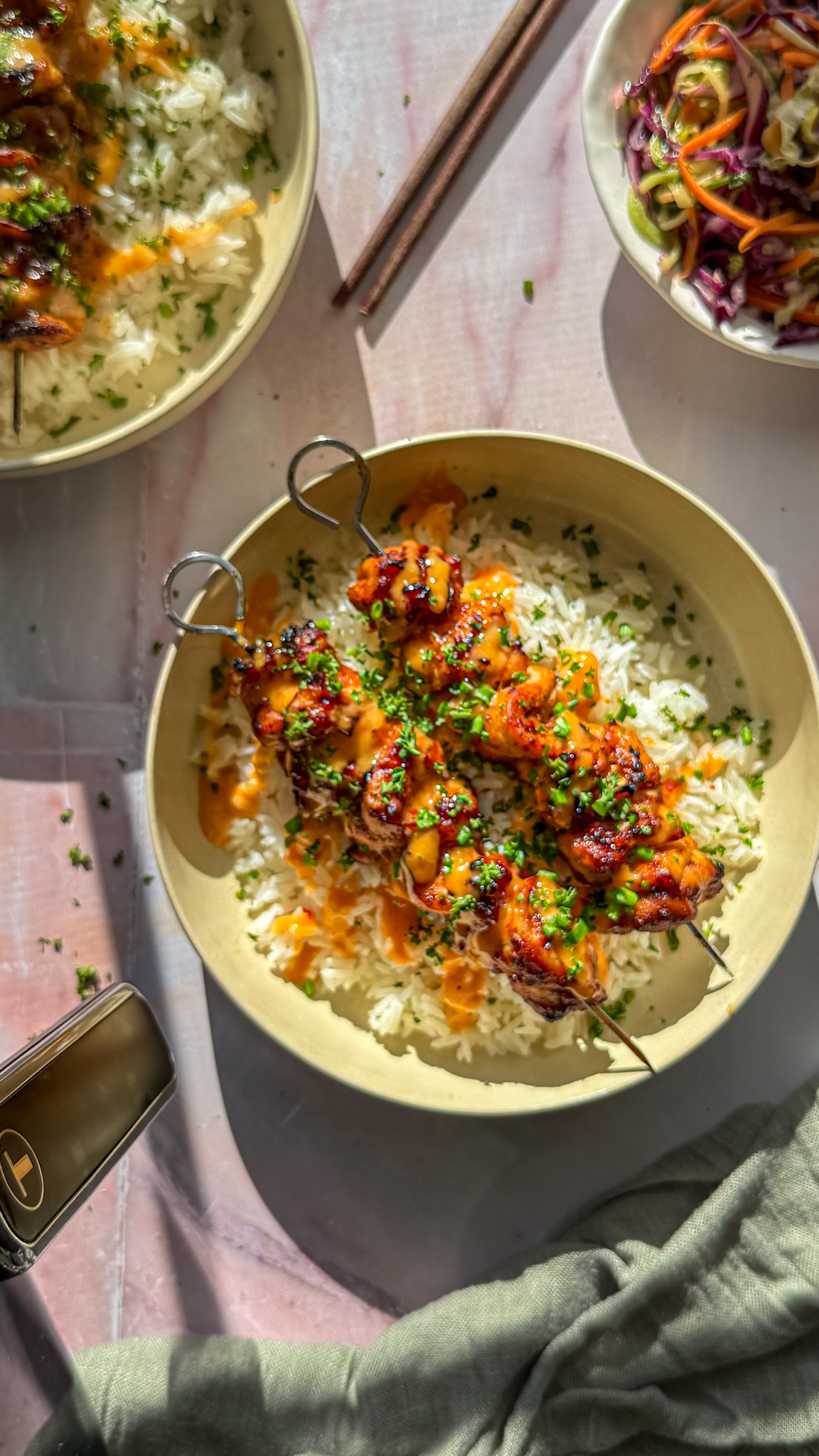 grilled bang bang chicken skewers over rice, drizzled with bang bang sauce. asian style cabbage salad and tfal air fryer around the main dish