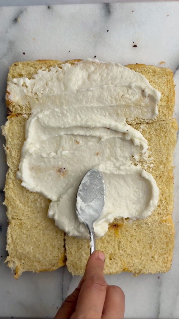 garlic sauce being spread on open dinner rolls