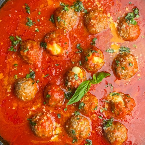 italian meatballs stuffed with cheese, in sauce topped with basil.