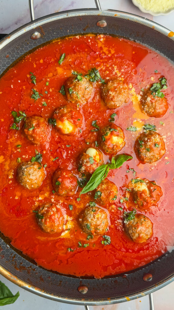 italian meatballs stuffed with cheese, in sauce topped with basil.