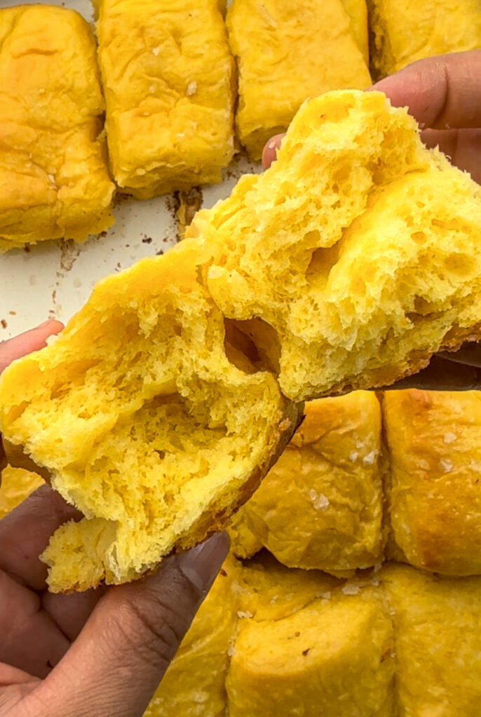 Open cross section of sweet potato Parker house rolls, torn in half to show the fluffy interior