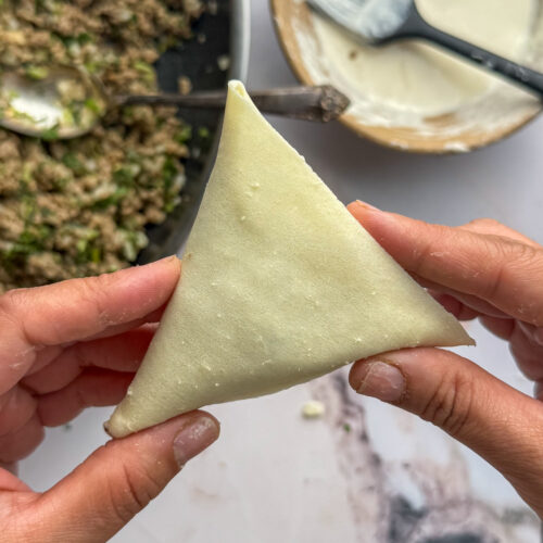 folded samosa with beef filling in the background